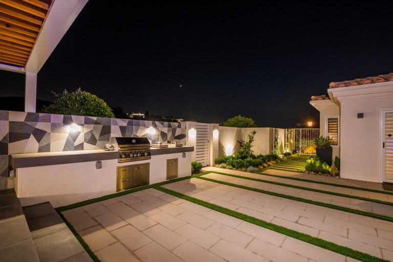 Example of a large trendy backyard concrete paver patio kitchen design in Orange County with a pergola
