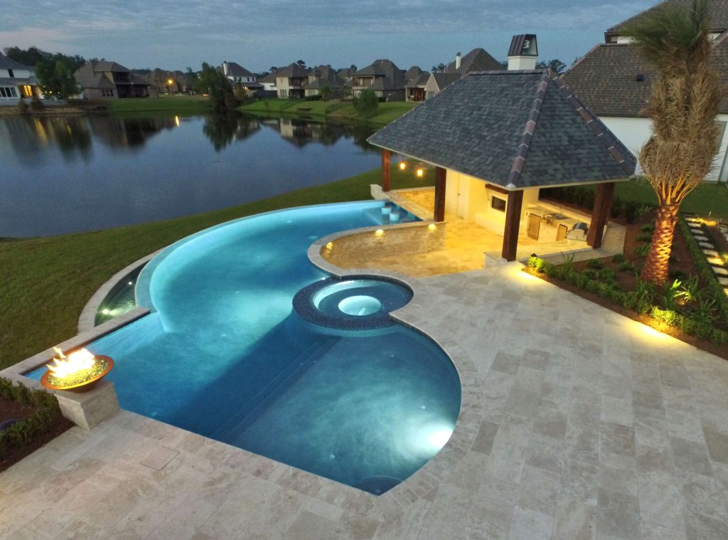 Example of a large trendy backyard custom-shaped infinity pool house design in New Orleans with decking