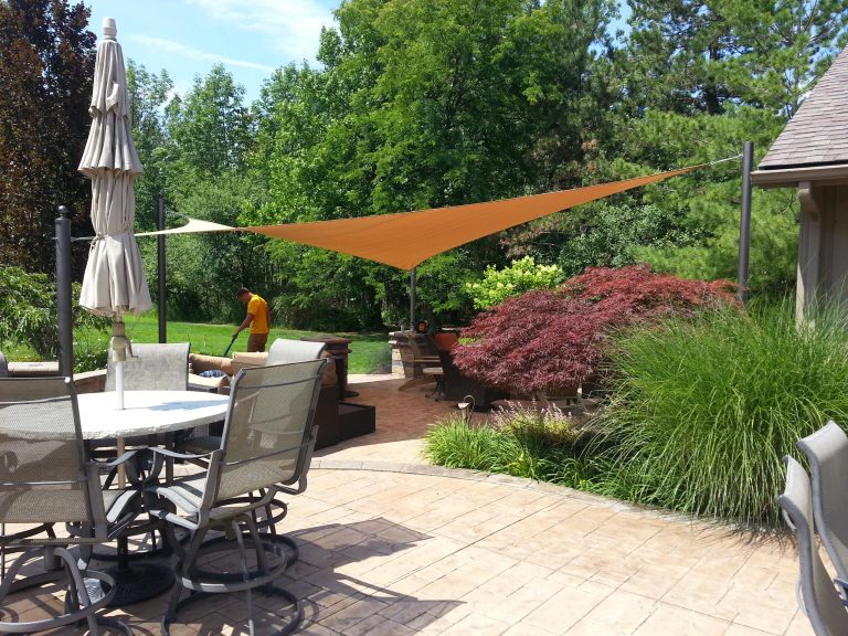 Example of a large trendy backyard stamped concrete patio kitchen design in Cleveland with an awning
