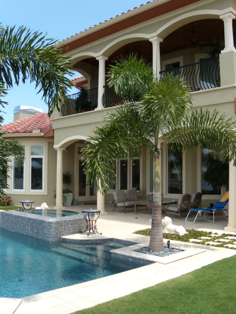 Example of a large trendy backyard stone and custom-shaped infinity hot tub design in Tampa