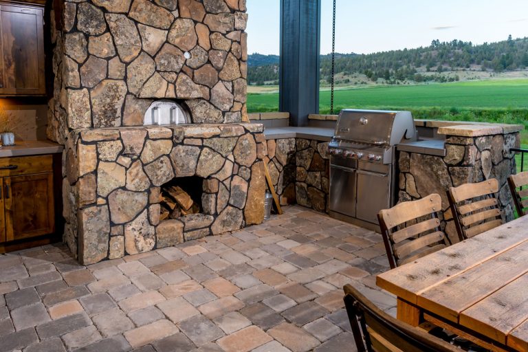Example of a large tuscan backyard brick patio kitchen design in Other
