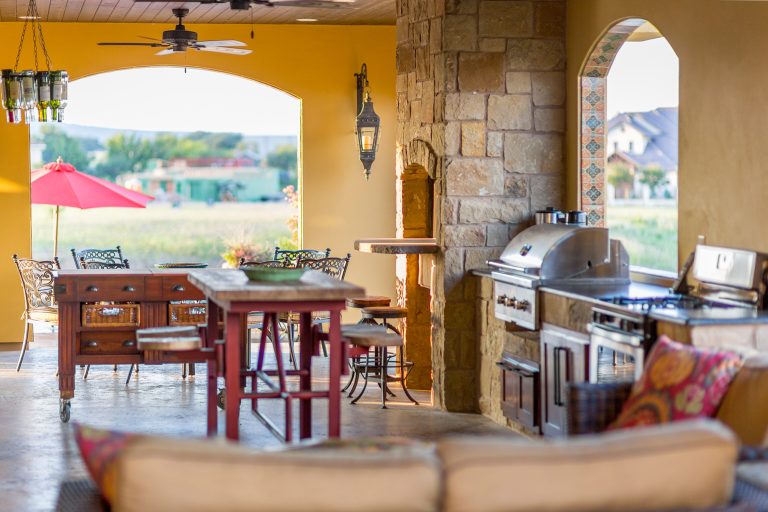 Example of a large tuscan backyard tile patio kitchen design in Austin with a roof extension