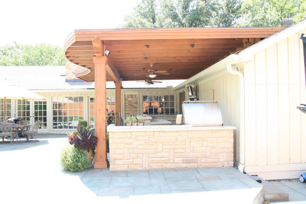 Example of a mid-sized backyard stamped concrete patio kitchen design in Dallas with a roof extension