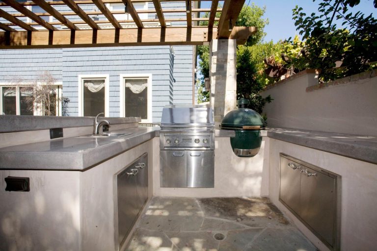 Example of a mid-sized backyard stone patio kitchen design in Los Angeles with a pergola