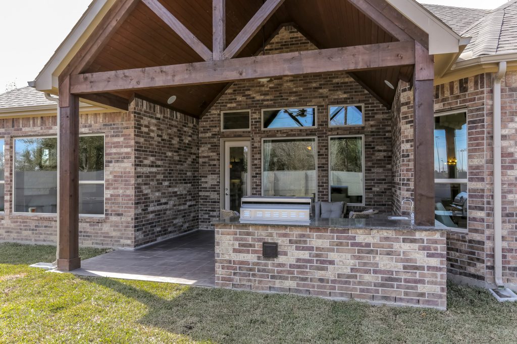 Example of a mid-sized backyard tile patio kitchen design in Houston with a roof extension