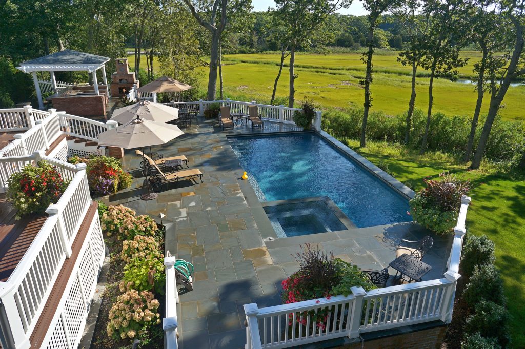 Example of a mid-sized classic backyard stone and l-shaped lap hot tub design in Other