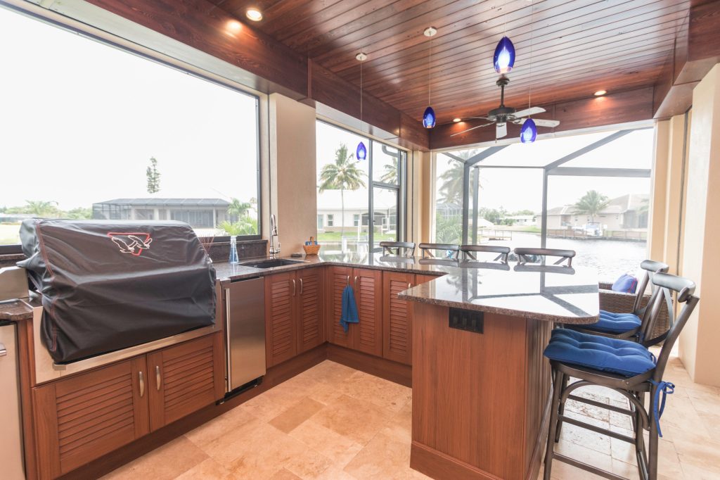 Example of a mid-sized classic backyard tile patio kitchen design in Miami with a roof extension