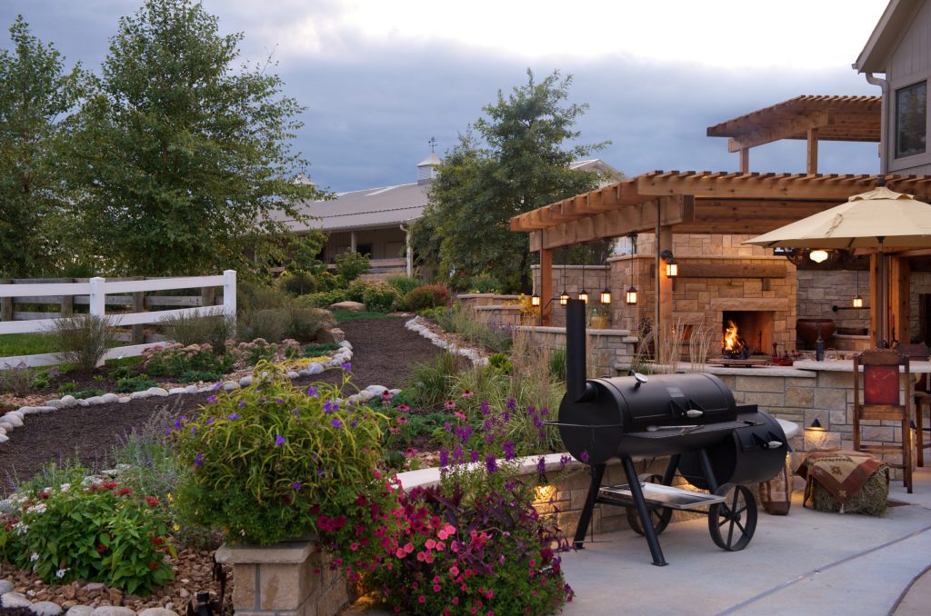 Example of a mid-sized country backyard concrete patio kitchen design in Kansas City with a pergola
