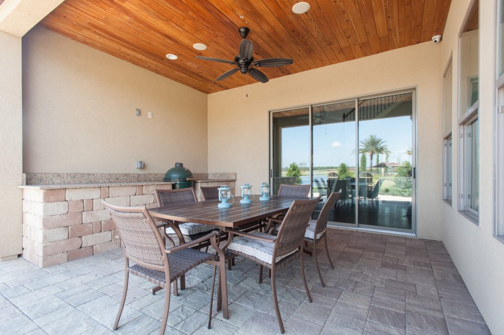 Example of a mid-sized farmhouse backyard concrete paver patio kitchen design in Jacksonville with a roof extension