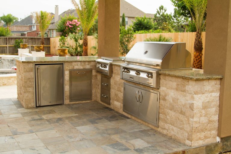 Example of a mid-sized island style backyard stone patio kitchen design in Houston with a gazebo