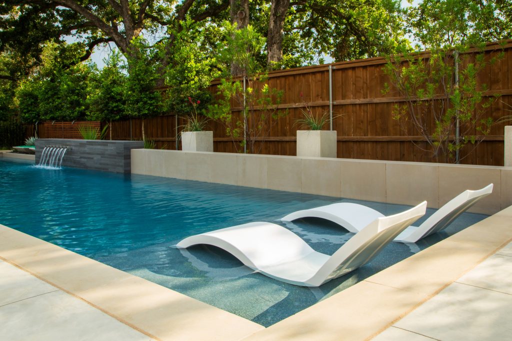 Example of a mid-sized minimalist backyard rectangular pool fountain design in Dallas with decking