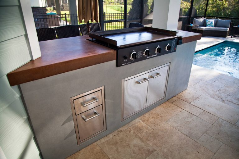 Example of a mid-sized minimalist backyard stone patio kitchen design in Jacksonville with a roof extension