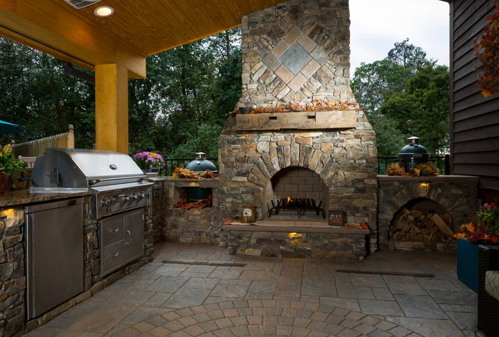 Example of a mid-sized mountain style backyard concrete paver patio kitchen design in Raleigh with a roof extension