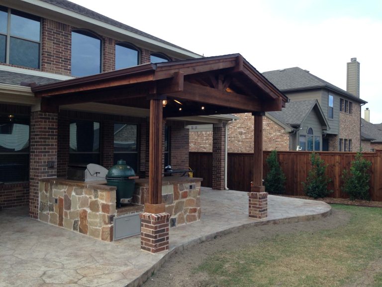 Example of a mid-sized mountain style backyard stamped concrete patio kitchen design in Dallas with an awning