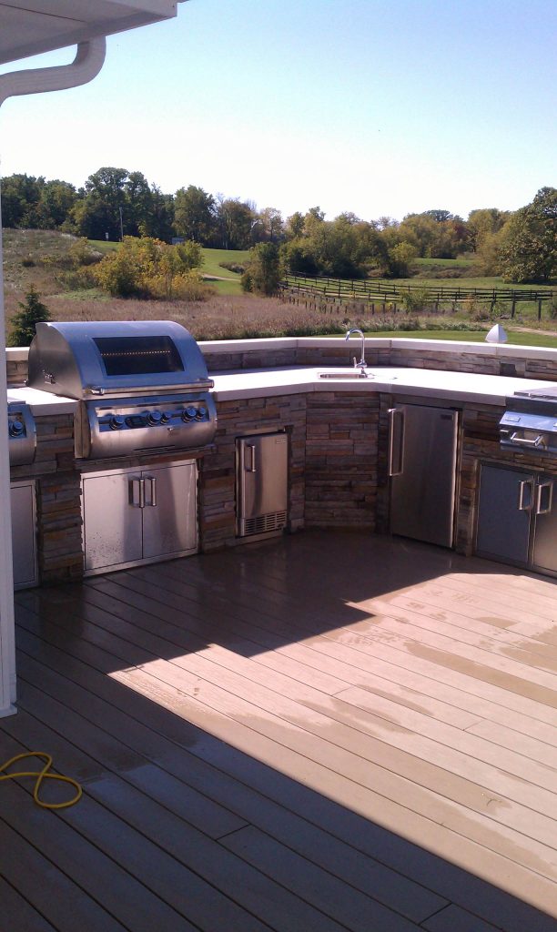 Example of a mid-sized transitional backyard patio kitchen design in Milwaukee with decking and no cover