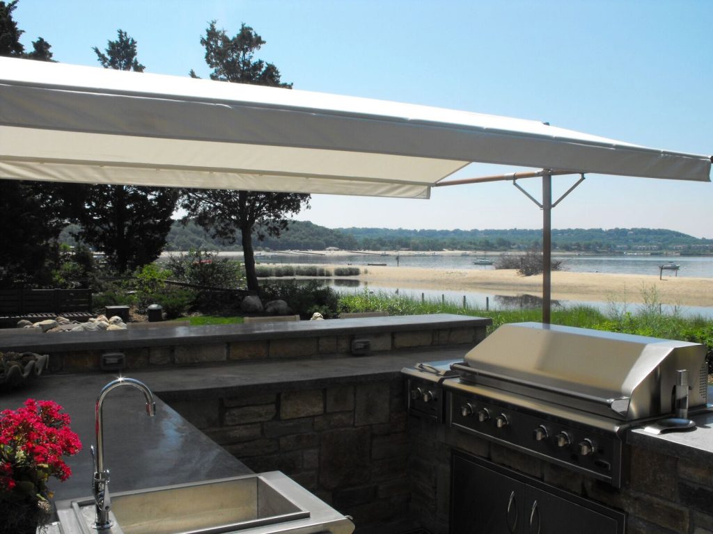 Example of a mid-sized transitional backyard patio kitchen design in New York with an awning