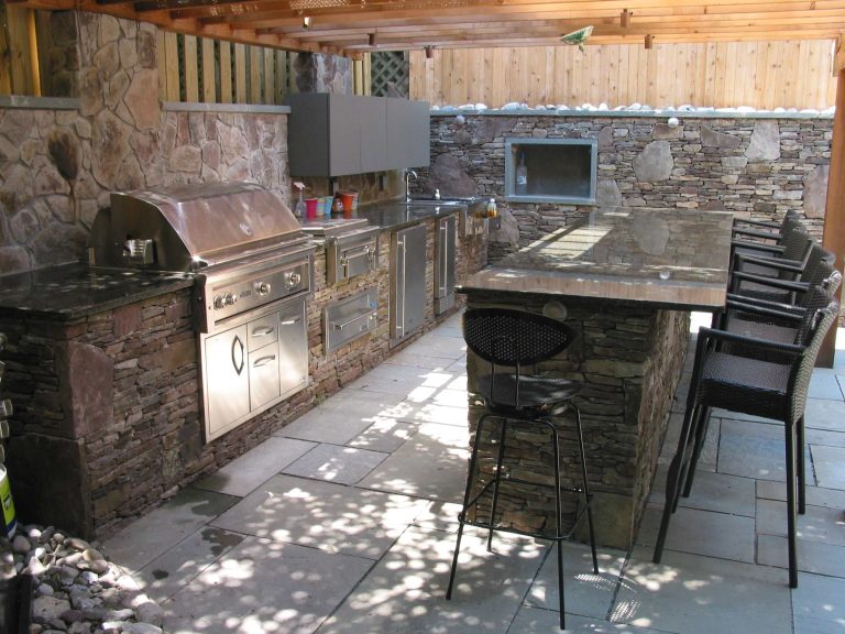 Example of a mid-sized transitional backyard stone patio kitchen design in Baltimore with a pergola