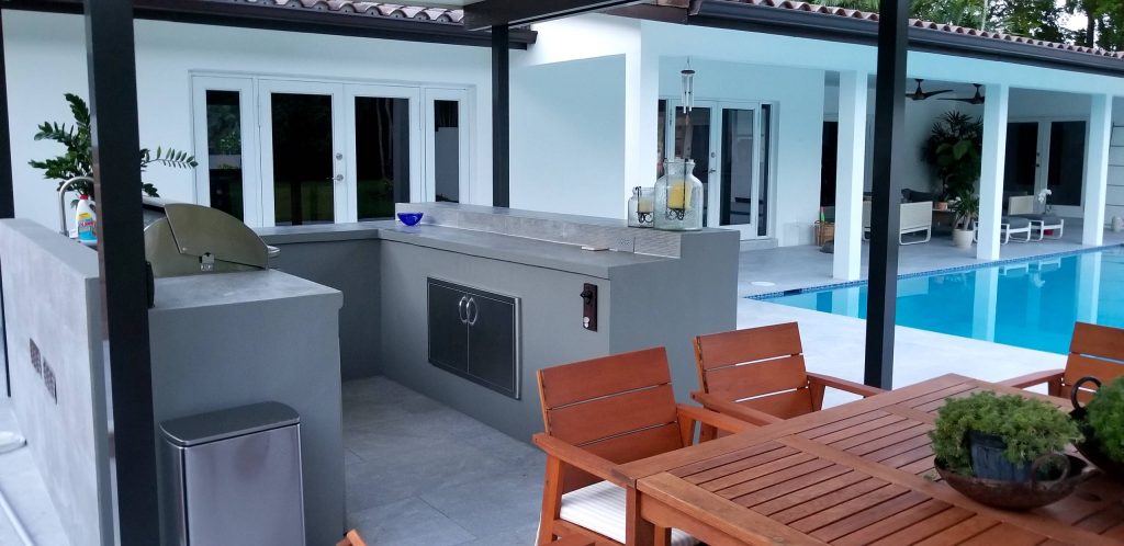 Example of a mid-sized trendy backyard concrete paver patio kitchen design in Miami with a roof extension