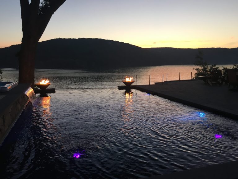 Example of a mid-sized trendy backyard stone and rectangular infinity pool fountain design in New York