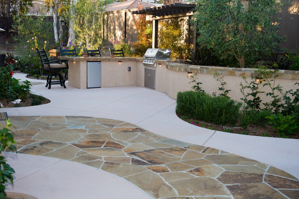 Example of a mid-sized trendy backyard stone patio kitchen design in San Diego with a pergola