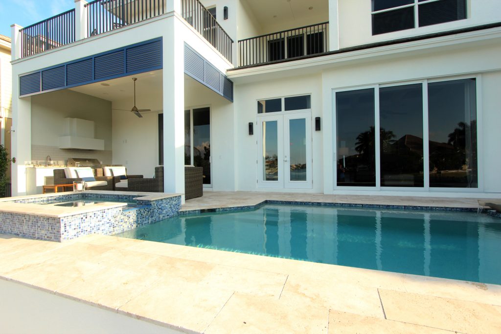 Example of a minimalist backyard stone patio kitchen design in Miami with a roof extension