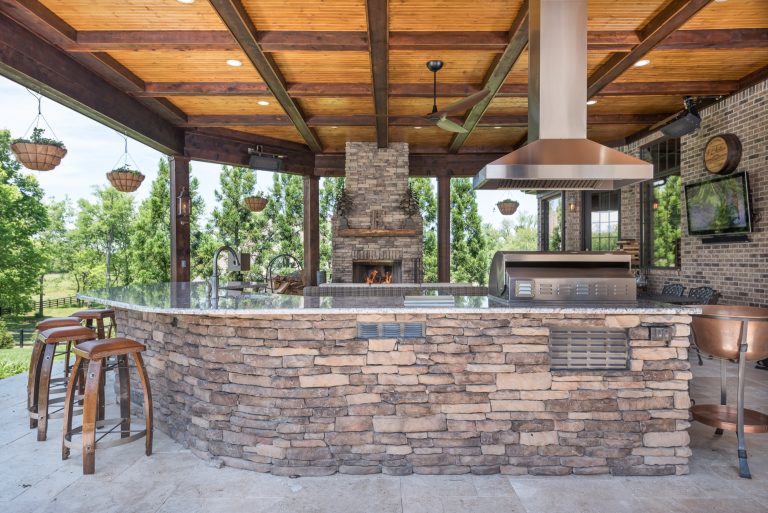 Example of a mountain style backyard stone patio kitchen design in Other with a roof extension