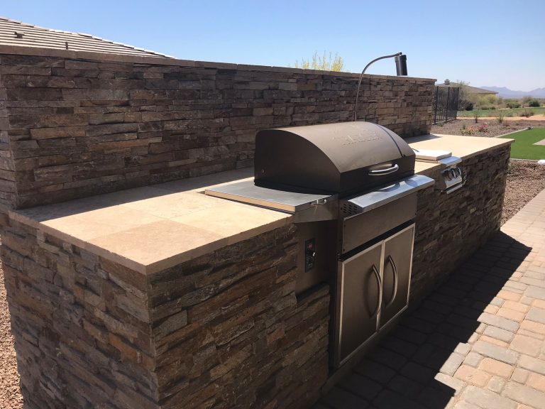 Example of a mountain style backyard stone patio kitchen design in Phoenix
