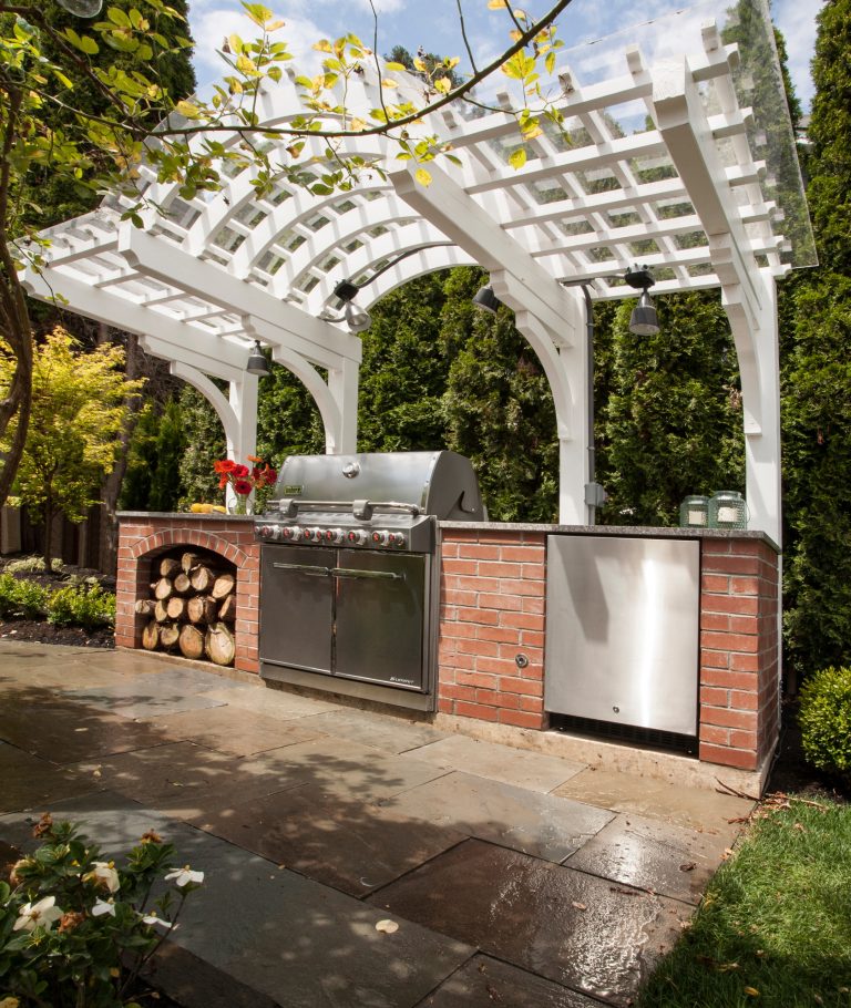 Example of a small classic backyard stone patio kitchen design in Seattle with a pergola