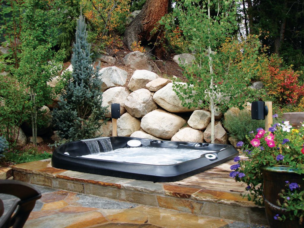 Example of a small island style backyard stone and rectangular aboveground hot tub design in Tampa