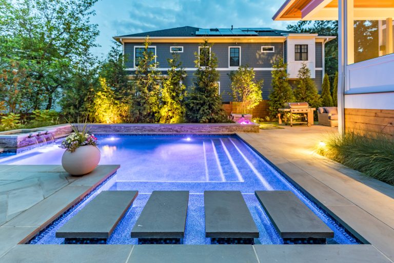 Example of a small minimalist backyard stone and rectangular pool fountain design in DC Metro