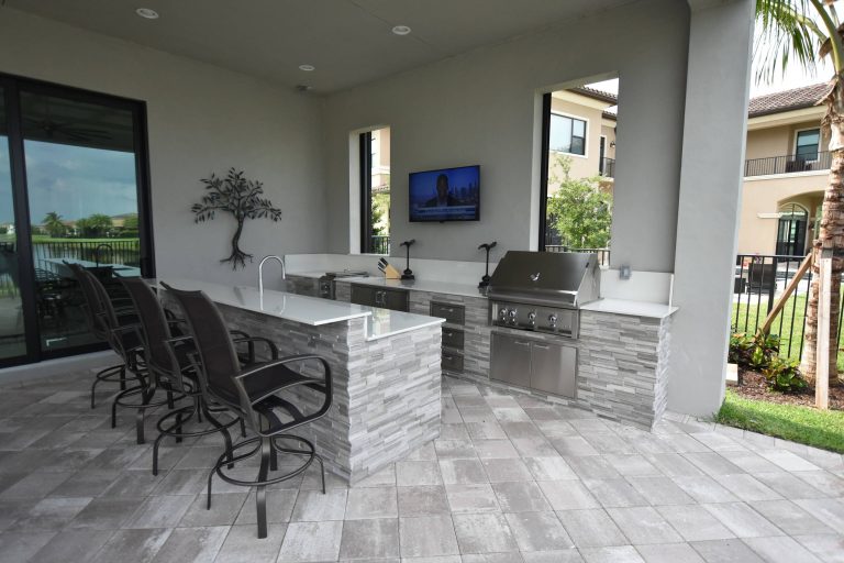 Example of a trendy backyard concrete paver patio kitchen design in Miami with a roof extension