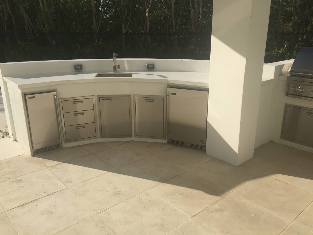 Example of an island style backyard stone patio kitchen design in Miami with a roof extension