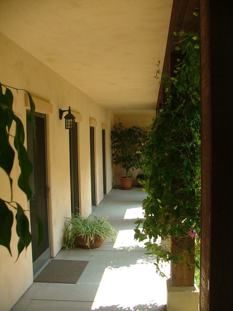Exterior covered walk provides shelter from the elements and natural lighting into adjacent interior circulation hallway.