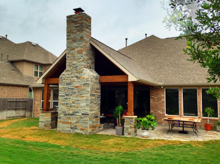 External view of this patio highlights the massive stone fireplace and matching stone footings on the cedar-wrapped beams, plus an extended patio area.