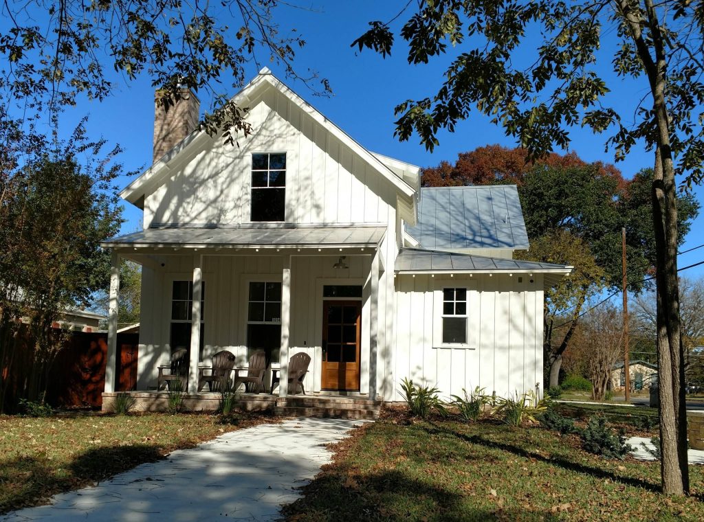 Farmhouse style vacation house with painted board & batten siding and trim and standing seam metal roof.