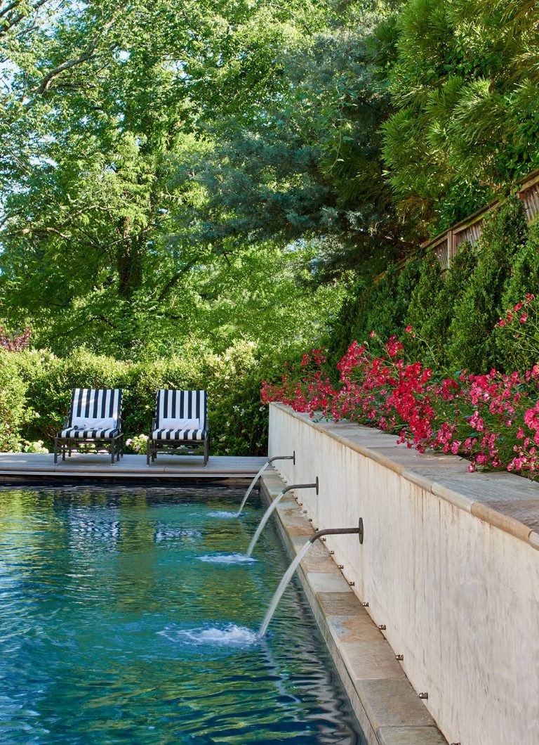 Fountains rain water from a landscaped terrace over the pool.