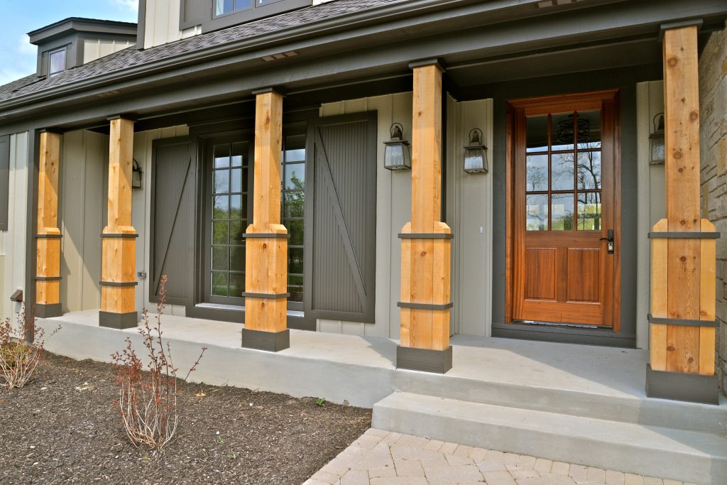 Front Porch with Wooden Columns, and a set of French Doors with charcoal shutters