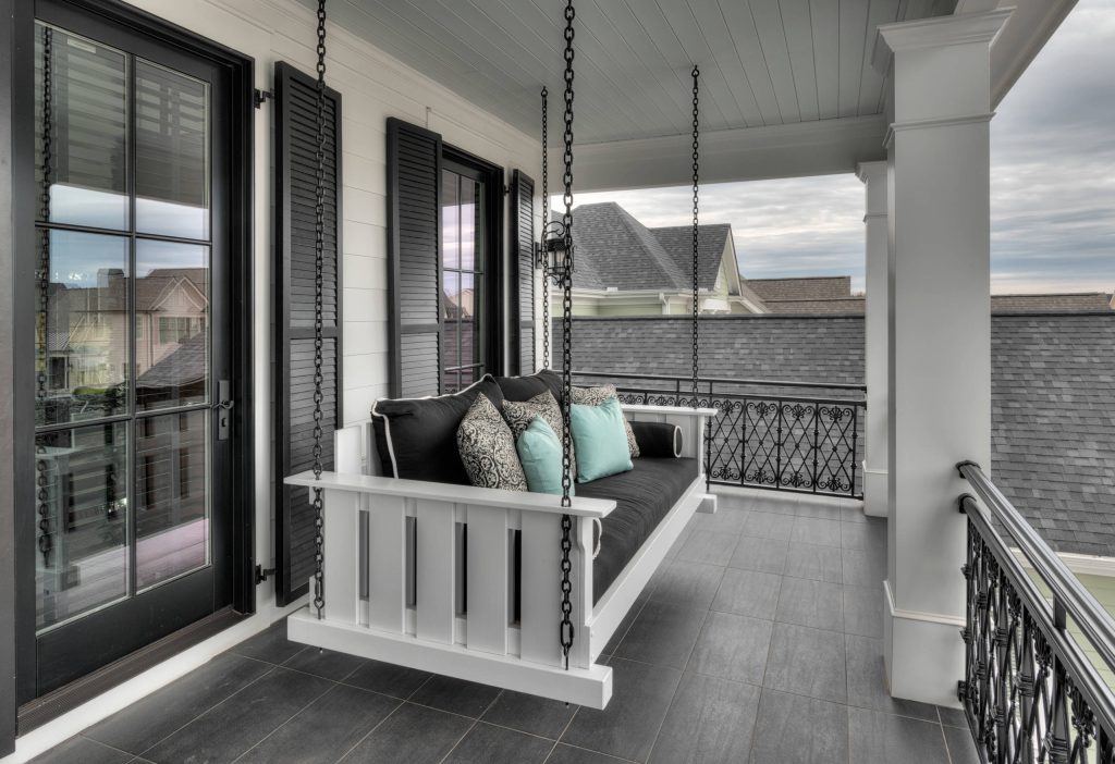 Front porch living at its finest, tiled patio flooring. Decorative wrought iron railing with custom swinging day bed/ couch.