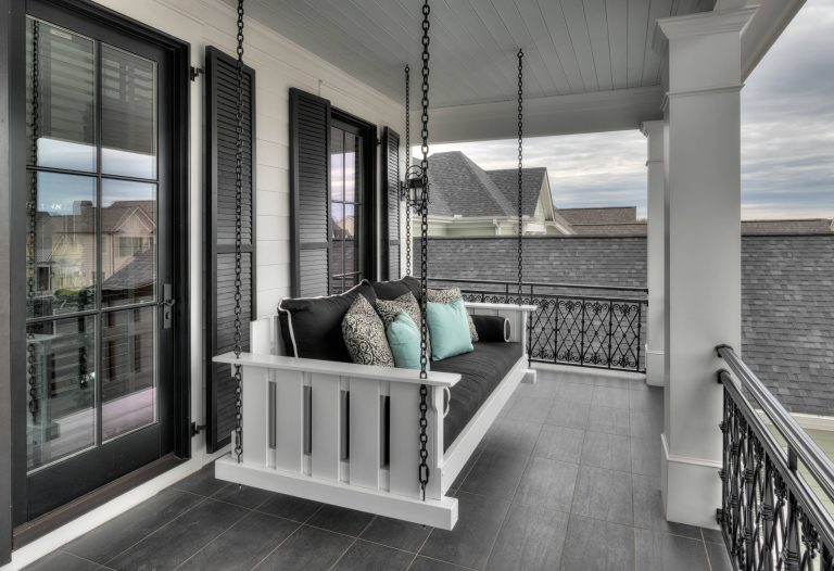 Front porch living at its finest, tiled patio flooring. Decorative wrought iron railing with custom swinging day bed/ couch.