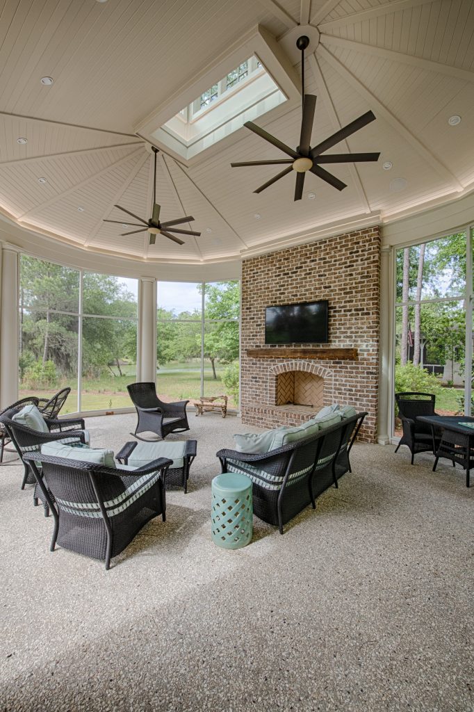 Gazebo-style round screened porch with a vaulted ceiling, cupola, tabby floors, outdoor fireplace, and lagoon views.