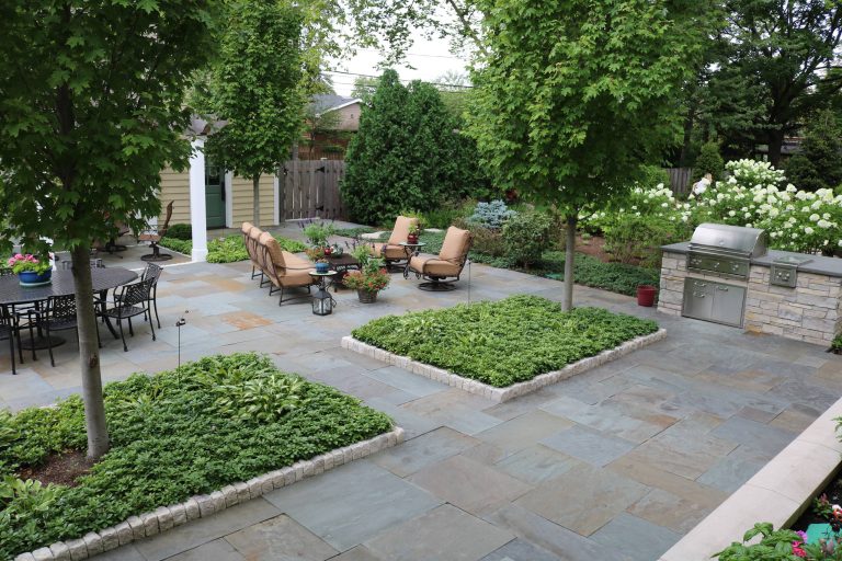 Generous island planting beds, filled with a mix of pachysandra and hosta, are edged in natural Valders stone cobbles. Full range bluestone patio and island grill. Photo by Terra Jenkins and Kirsten Gentry