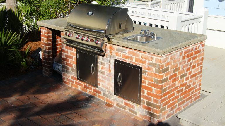 Hardscaping extends to this gorgeous outdoor kitchen area! Rustic brick wraps around all four sides, with a rough-edge slate top perfect for food prep and conversation with friends over drinks.