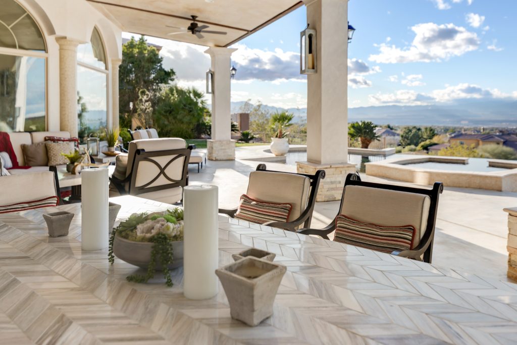 Huge elegant backyard stamped concrete patio kitchen photo in Las Vegas with a roof extension