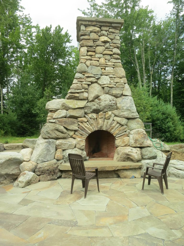 Huge mountain style backyard stone patio kitchen photo in Burlington with no cover
