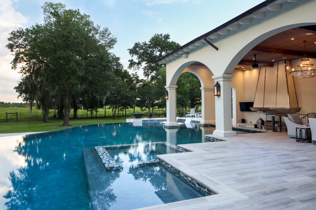 Huge transitional backyard stone patio kitchen photo in New Orleans with a roof extension