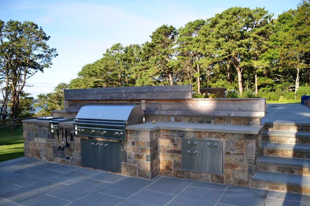 Huge transitional backyard stone patio kitchen photo in New York with a pergola