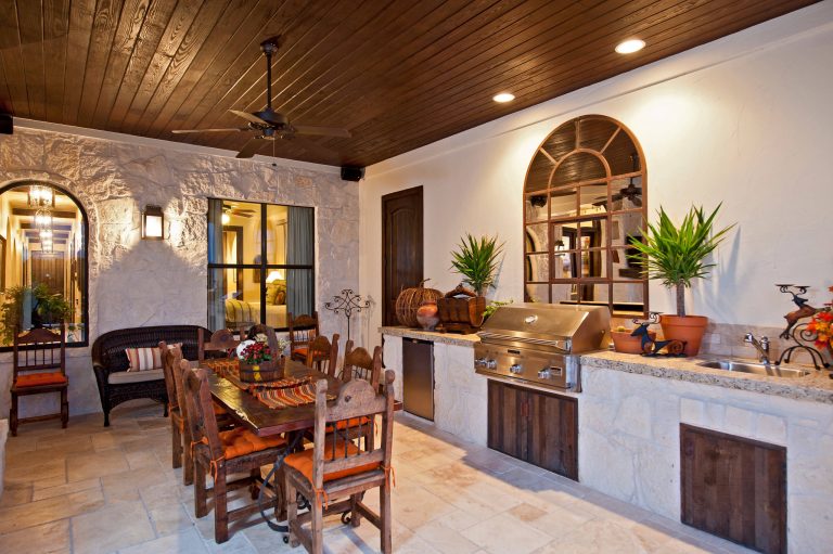 Huge tuscan backyard stone patio kitchen photo in Austin with a roof extension