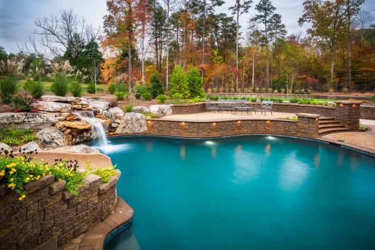 Inground swimming pool with slide, waterfall, sun shelf, lounging ledge, firepit and raised patio. Techo bloc, Pebble Tec, LED lights and full chlorine free (Clearswim) sanitation and automation. JSilkstonePhotos