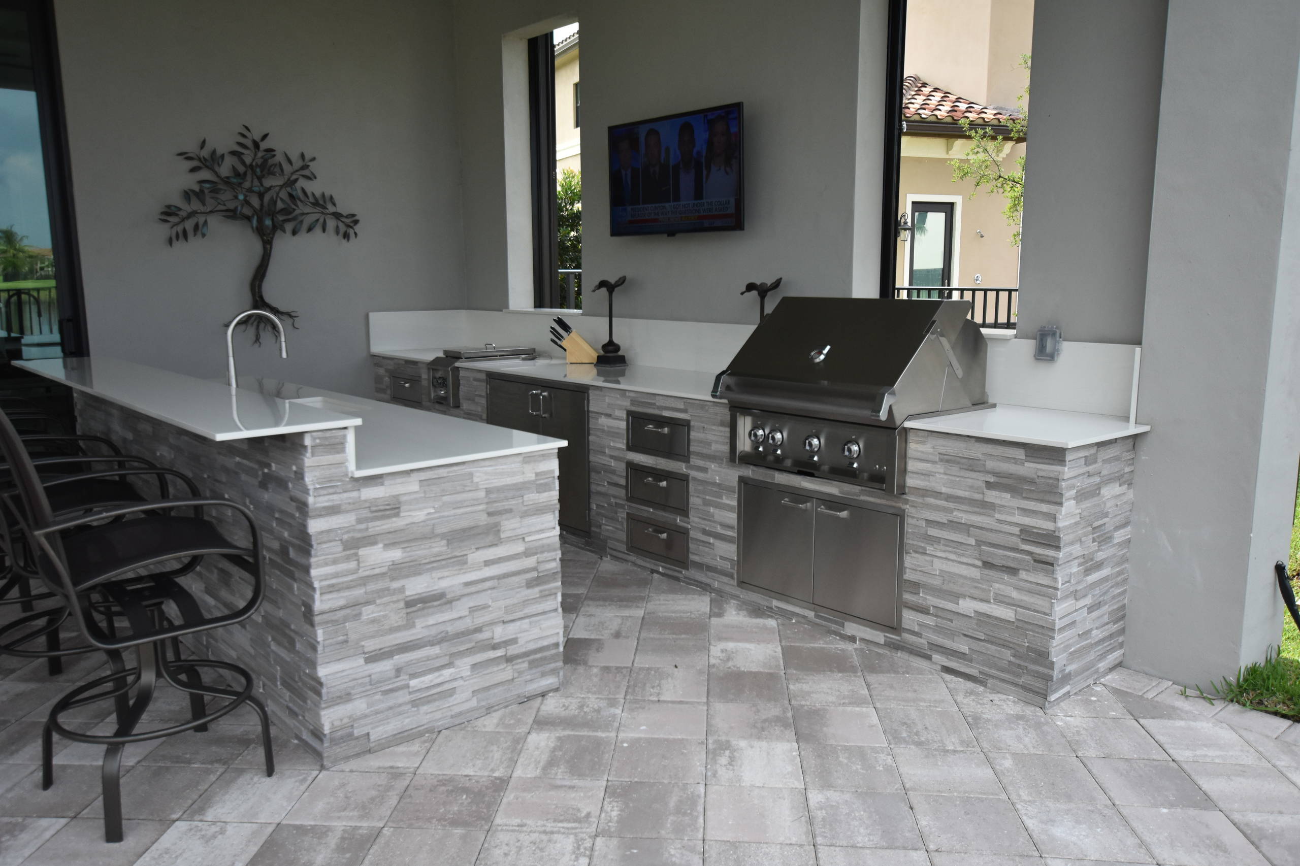 Inspiration for a contemporary backyard concrete paver patio kitchen remodel in Miami with a roof extension