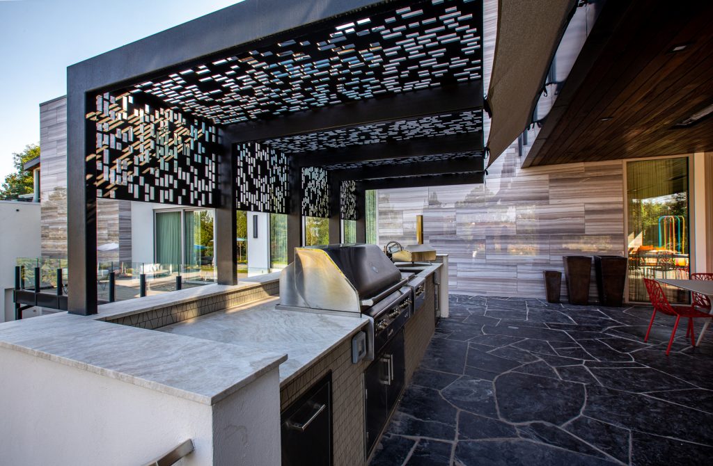 Inspiration for a huge contemporary backyard stone patio kitchen remodel in Salt Lake City with a pergola